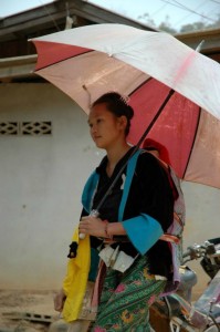 Kvinde med parasol og barn på ryggen